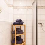 Badezimmer mit Dusche, Holzregal und gefalteten Handtüchern