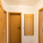 Flur mit Holztüren und Kleiderhaken an der Wand.
