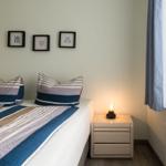 Schlafzimmer mit Bett, Nachttisch und Fenster mit Vorhängen.