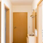 Flur mit Holztüren, Spiegelschrank und Haken für Kleidung.