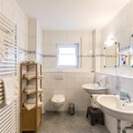 Badezimmer mit Toilette, Waschbecken und Heizkörper. Handtücher aufgestellt.