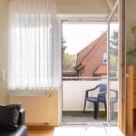 Durch die Glastür gelangt man auf die Terrasse mit Stuhl. Im Raum steht ein Sofa und ein Schrank.