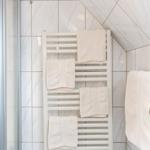 Badezimmer mit Heizkörper und weißen Handtüchern an der Wand.