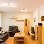 Wohnzimmer mit Ledersofa, Ledersessel, Holztisch und Holzmöbel.