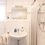 Badezimmer mit Dusche, Waschbecken und Fenster.