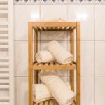 Holzregal mit Handtüchern in Badezimmer mit Fliesenwand und Heizung.
