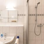 Badezimmer mit Dusche, Waschbecken und Spiegel
