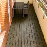 Terrasse mit Tisch und zwei Stühlen, Holzdielen und Brüstung.