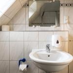 Badezimmer mit Waschbecken, Spiegel, Handtuchhalter und Haartrockner an der Wand.