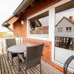 Terrasse mit Tisch und Stühlen, Blick auf Grünland und Haus.