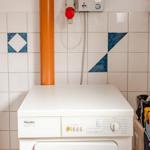 Waschmaschine mit Trockneranlage an Wand mit Fliesen
