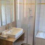 Badezimmer mit Dusche, Badewanne und Waschbecken mit Spiegel.