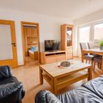 Wohnzimmer mit Essbereich, TV und Blick auf die Straße.