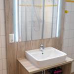 Badezimmer mit Waschbecken, Spiegel und Dusche