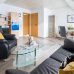 Wohnzimmer mit Sofa, Couchtisch und Essbereich unter Dachschräge