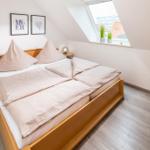 Schlafzimmer mit Dachschrägen, Bett, Nachttisch und Stuhl. Fenster mit Blick auf Dächer.