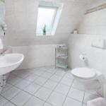 Badezimmer mit Dusche, Toilette und Waschbecken unter Dachschrägen.