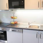 Küche mit Arbeitsfläche, Spüle, Kühlschrank und Kochfeld.