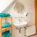 Badezimmer mit Waschbecken, Spiegel, Handtuchhalter und Heizkörper.