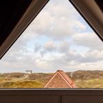 Dachfensterblick auf Dünenschilf und roten Ziegeldach