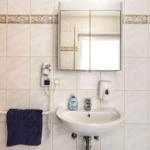 Badezimmer mit Waschbecken, Spiegel, Handtuch und Haartrockner an der Wand.