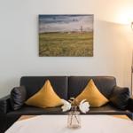 Schwarzes Sofa mit gelben Kissen, Wandbild und Stehlampe im Wohnzimmer.