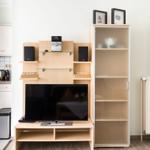 TV-Möbel mit Lautsprechern und Glasböden, daneben hängende Bilder und ein Schrank mit Glasfront.