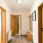 Flur mit Holztüren, Heizkörper und Kleiderhaken an der Wand.