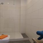 Dusche mit Duschbrause, Toilette und Handtücher auf Bänken