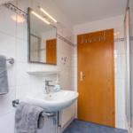 Badezimmer mit Dusche, Waschbecken und Spiegel
