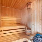 Holzsauna mit Sitzbank, Eimer und Steinkiste