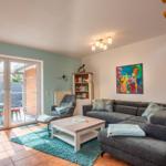 Wohnzimmer mit Sofa, Couchtisch und Terrassentür. Holztreppe und Wandbild sind sichtbar.
