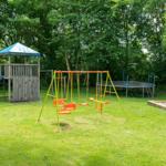 Großer Garten mit Spielplatz, Schaukel, Sandkasten und Trampolin.