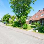 Eine Straße mit gepflastertem Boden, Bäumen und einem Haus mit rotem Dach.
