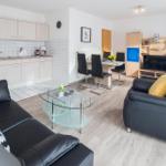 Wohn- und Essbereich mit Küche, Sofa, Sessel und Fernseher.