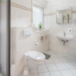Badezimmer mit Dusche, Toilette, Waschbecken und Spiegel