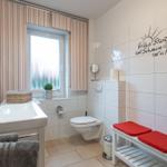 Badezimmer mit Toilette, Waschbecken und rotem Sitzbank