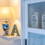 Schrank mit Mehl- und Zuckerkanistern, Lampe und Buchstaben-A auf Regal.