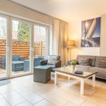 Wohnzimmer mit Sofa, Couchtisch und Terrasse mit Gartenmöbeln.