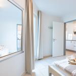 Schlafzimmer mit Spiegel, Bett und Blick in Küche.