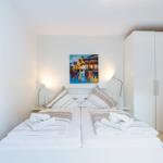 Schlafzimmer mit Doppelbett, Wandbild und Kleiderschrank.