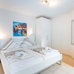Schlafzimmer mit Doppelbett, Kleiderschrank und Wandbild.