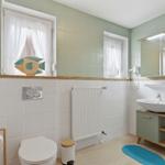 Badezimmer mit Toilette, Waschbecken und Badewanne. Fenster mit Fischmotiv.