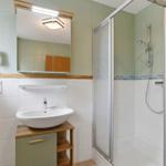 Badezimmer mit Dusche, Waschbecken und Spiegel