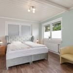 Schlafzimmer mit Doppelbett, gelber Sessel und Holzboden.