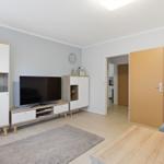 Wohnzimmer mit Fernseher, Holzmöbeln und Tür zum Flur.
