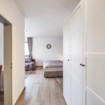Schlafzimmer mit Bett, Sofa und Kleiderschrank. Holzboden und Wanduhr sichtbar.