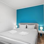 Schlafzimmer mit Bett, blauer Wand und Nachttischen mit Lampen.