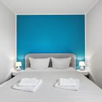 Schlafzimmer mit Bett, zwei Nachttischen und blauer Wand hinter dem Kopfteil.