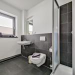 Badezimmer mit Dusche, Toilette und Waschbecken. Fenster mit Handtüchern.